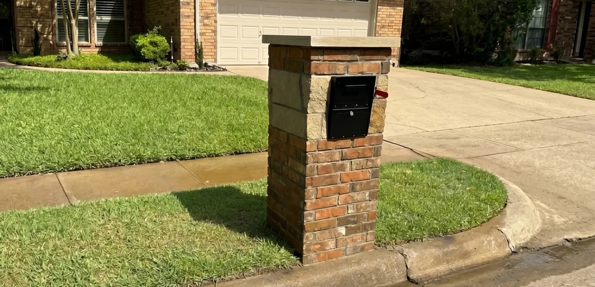 Custom brick mailbox built by Parker County Masonry in front of a brick home