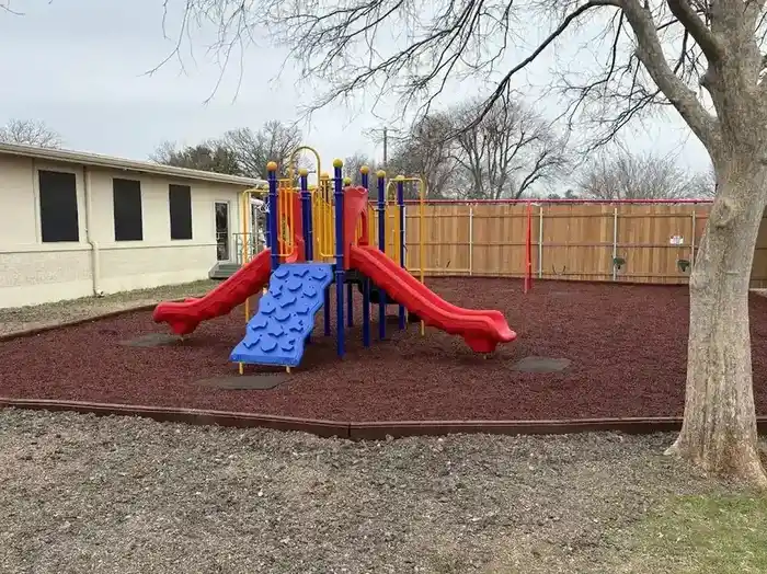 Commercial playground with climbing wall, dual slides, and safety surfacing installation
