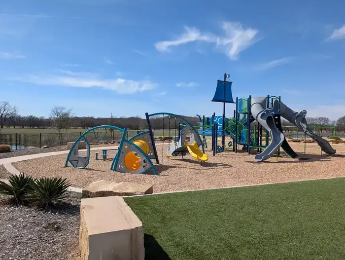 Full view of commercial playground with multiple play structures, slides, and landscaped borders