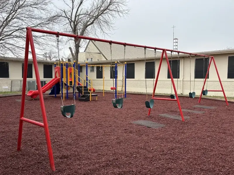 Commercial playground with swing set and play structure featuring rubber mulch safety surfacing